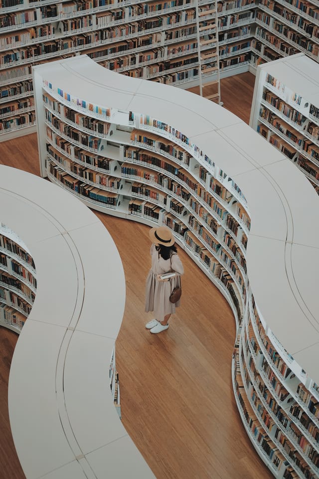 A person standing among winding bookshelves.